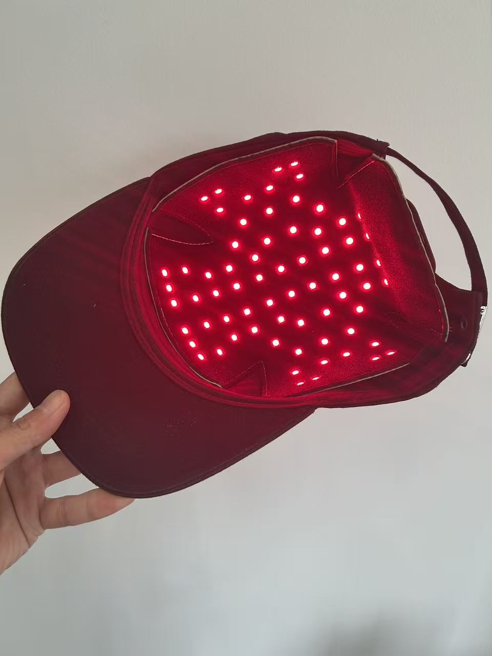 Black cap fitted with the graphene photon hair-care pad, red LEDs lit across the insert